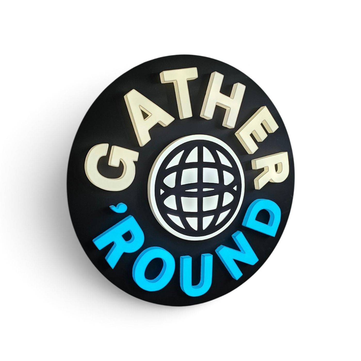 Logo luminos rotund „Gather 'Round”, cu glob stilizat, în crem şi albastru pe disc negru